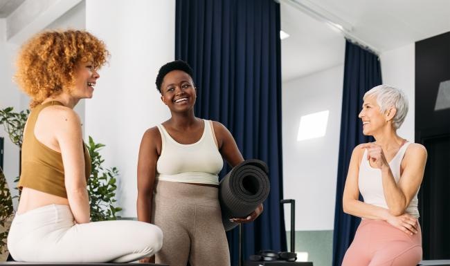 a person holding a yoga mat standing next to a person sitting on a chair